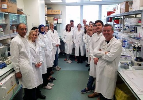 Group of men and women wearing while lab coats in their lan