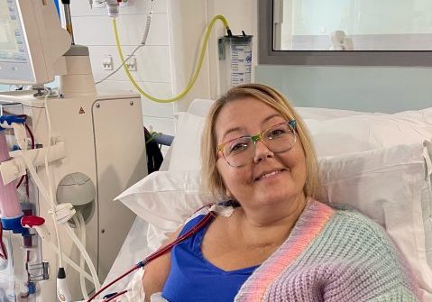 Female in a hospital bed receiving dialysis, smiling for the camera