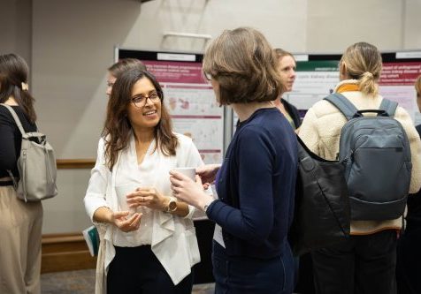 People networking at the event. The image focuses on two females talking to each other while holding coffee cups.