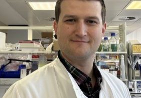 Peter in his lab, wearing a white lab coat.