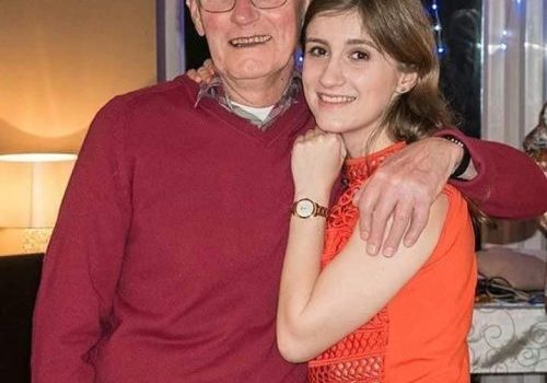 Father and daughter with arms around shoulders smiling for picture