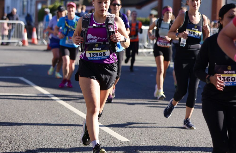 Female running during an event wearing purple running vest and shorts