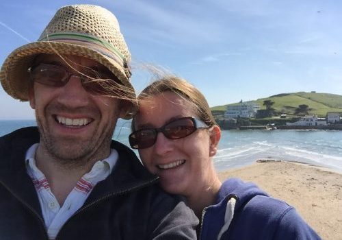 Gareth and Caroline Prodger Husband and wife on windy beach, taking a selfie with sea in the background