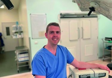 Male doctor, wearing blue scrubs, in a research lad
