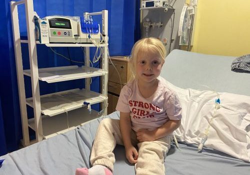 6 year old girl sitting on a hospital bed having dialysis.