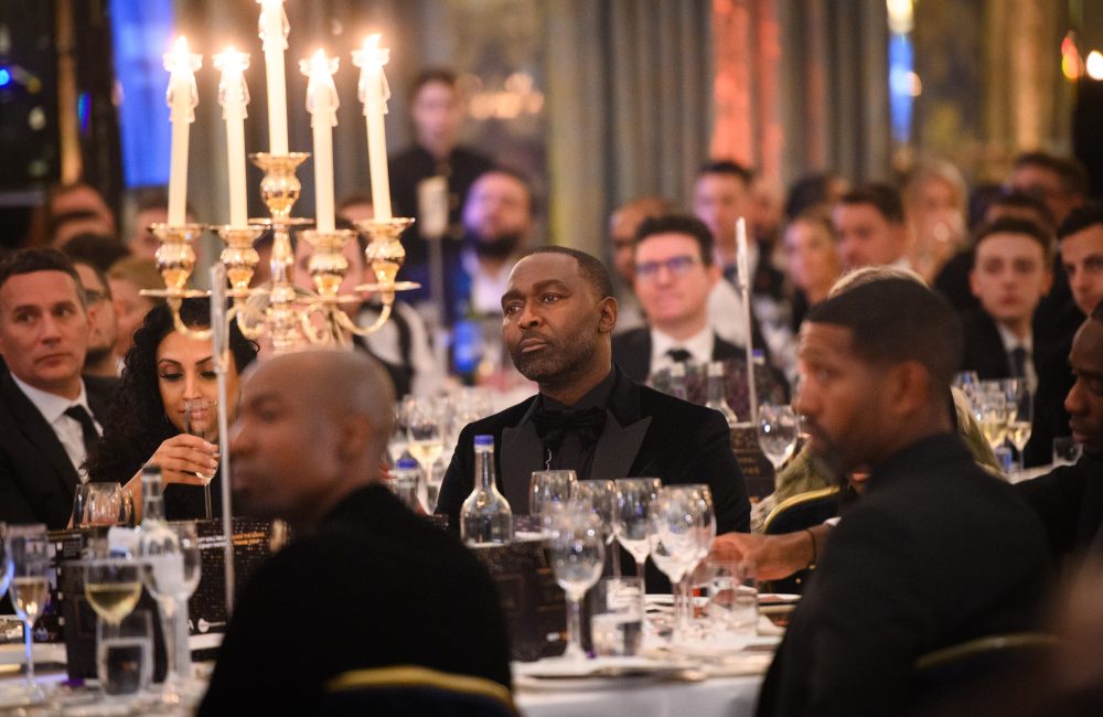 Group of men sat at a table at the gala event with wine glasses and candelabra in front of them
