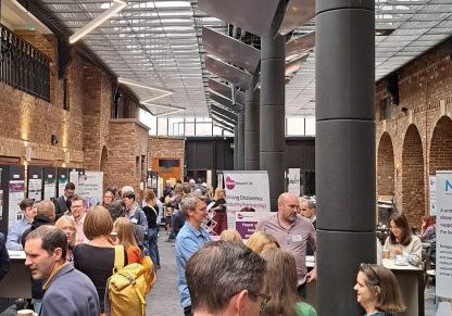 Research posters on display in large room with people viewing them and networking