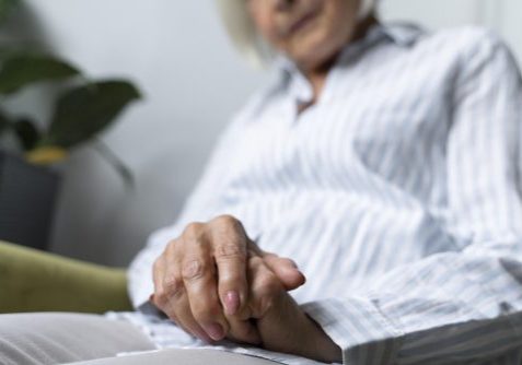 Older lady sitting on chair with a close up of her hands. You can't see her face.