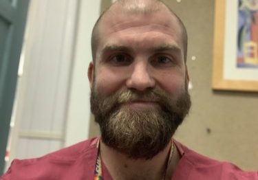 Male with beard wearing red scrubs