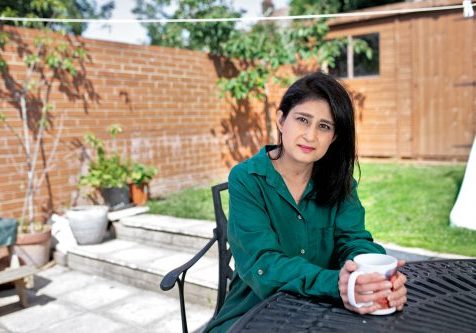 Kidney patient Sabina sitting at a table in her garden.