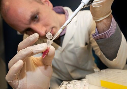 Dr Simon Baker holding a pipette and vile