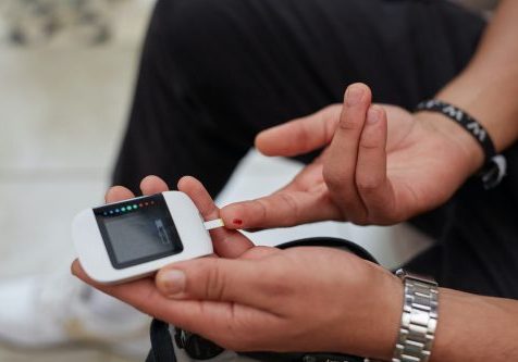 A young South African man with diabetes demonstrating blood glucose testing using gluco-meter.