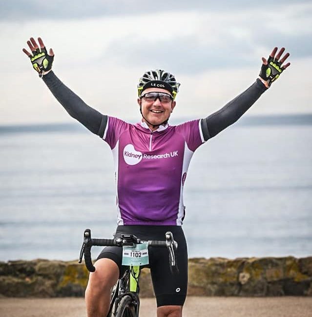Tony Knight with his arms in the air while riding his bike
