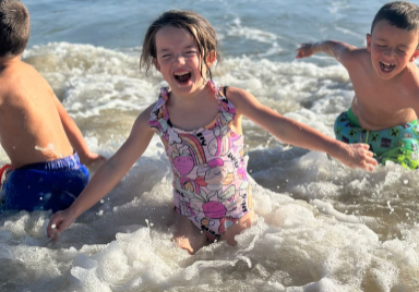 Young girl, in a patterned swimming costume, playing in the waves of the sea.